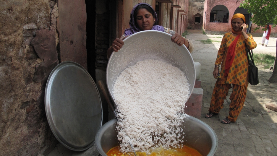 Santosh, one of the two cooks at this government school in Dujana, Haryana pours the rice into the cauldron of curried lentils and vegetables. Santosh, one of the two cooks at this government school in Dujana, Haryana pours the rice into the cauldron of curried lentils and vegetables.